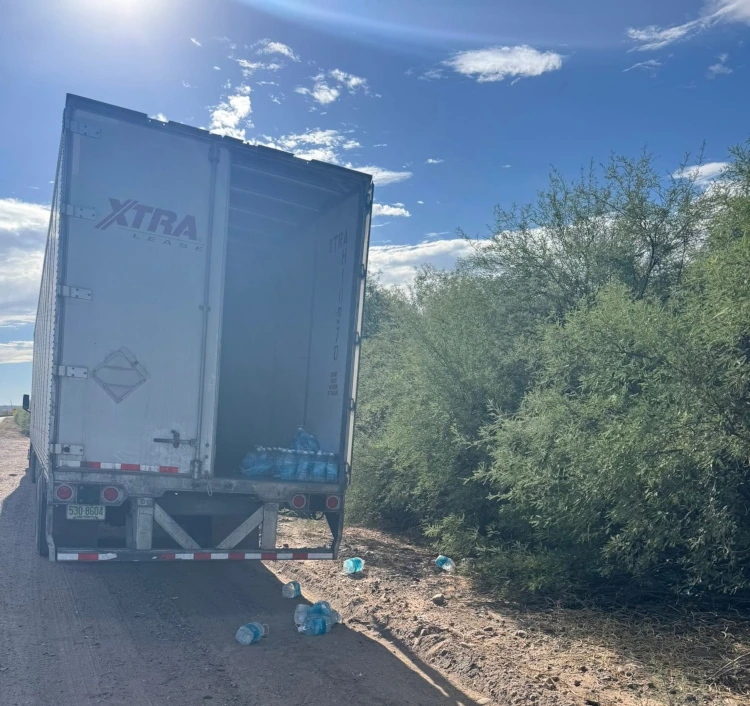 Truck with back door open and plastic water bottles in the truck and littered on the road