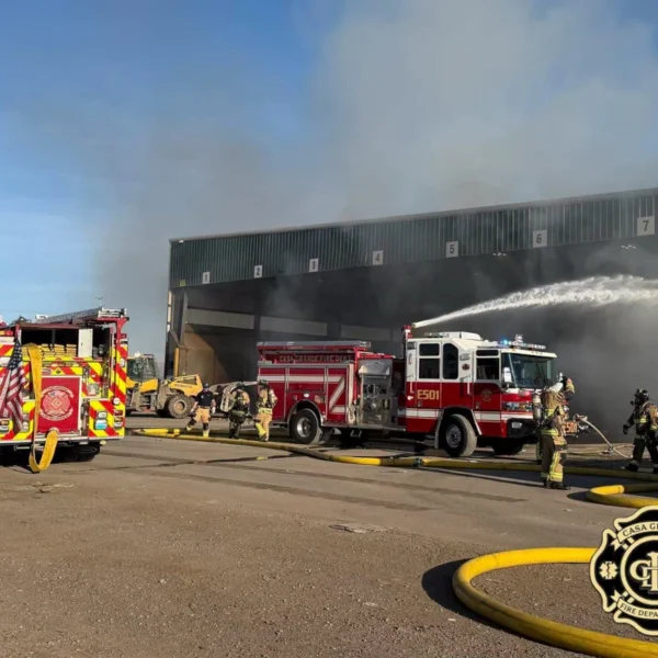 Fire engines and firefighters respond to the WM transfer station fire in Casa Grande, spraying water into a smoke-filled loading bay.