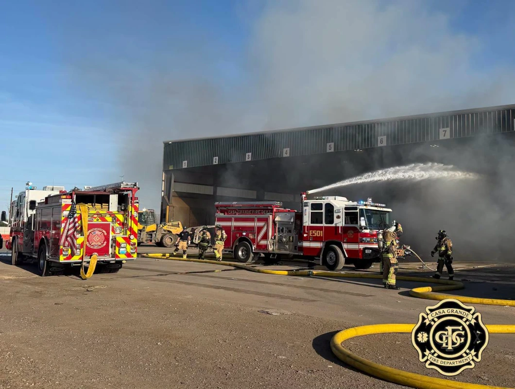 Fire engines and firefighters respond to the WM transfer station fire in Casa Grande, spraying water into a smoke-filled loading bay.