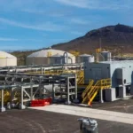 Storage tanks, piping and processing buildings at the Florence Copper facility, with Poston Butte rising in the background.