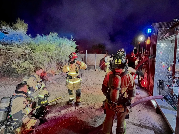 Superstition Fire and Medical District firefighters in full turnout gear stage next to an engine at night during the Apache Junction mobile home fire