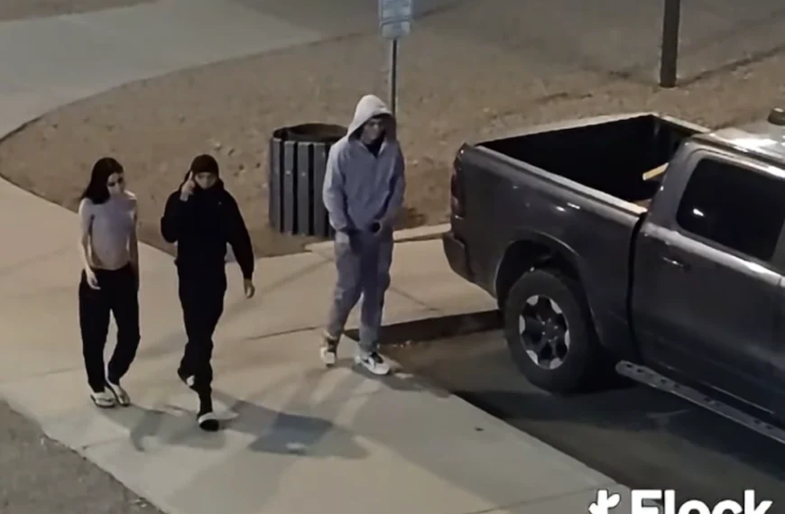 Three people walking on a sidewalk at night beside a parked pickup truck, in surveillance video released by police after a Casa Grande shooting.