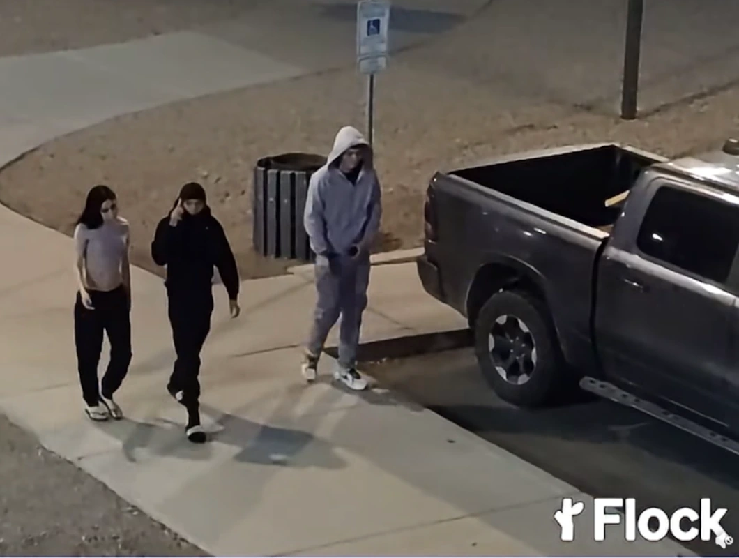 Three people walking on a sidewalk at night beside a parked pickup truck, in surveillance video released by police after a Casa Grande shooting.