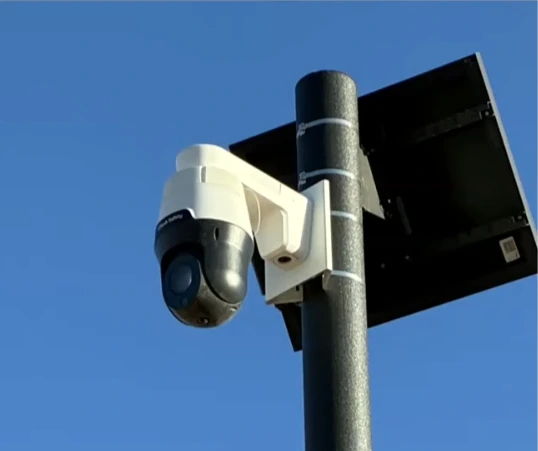 A solar-powered pan-tilt-zoom surveillance camera mounted on a pole.